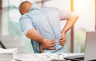 a man with his hands on his lower bank indicating he is in pain. He will need to follow return to work protocol in order to resume his duties.