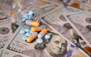 Pills and capsules in a bottle on US dollars bills. Representing the rising drug costs