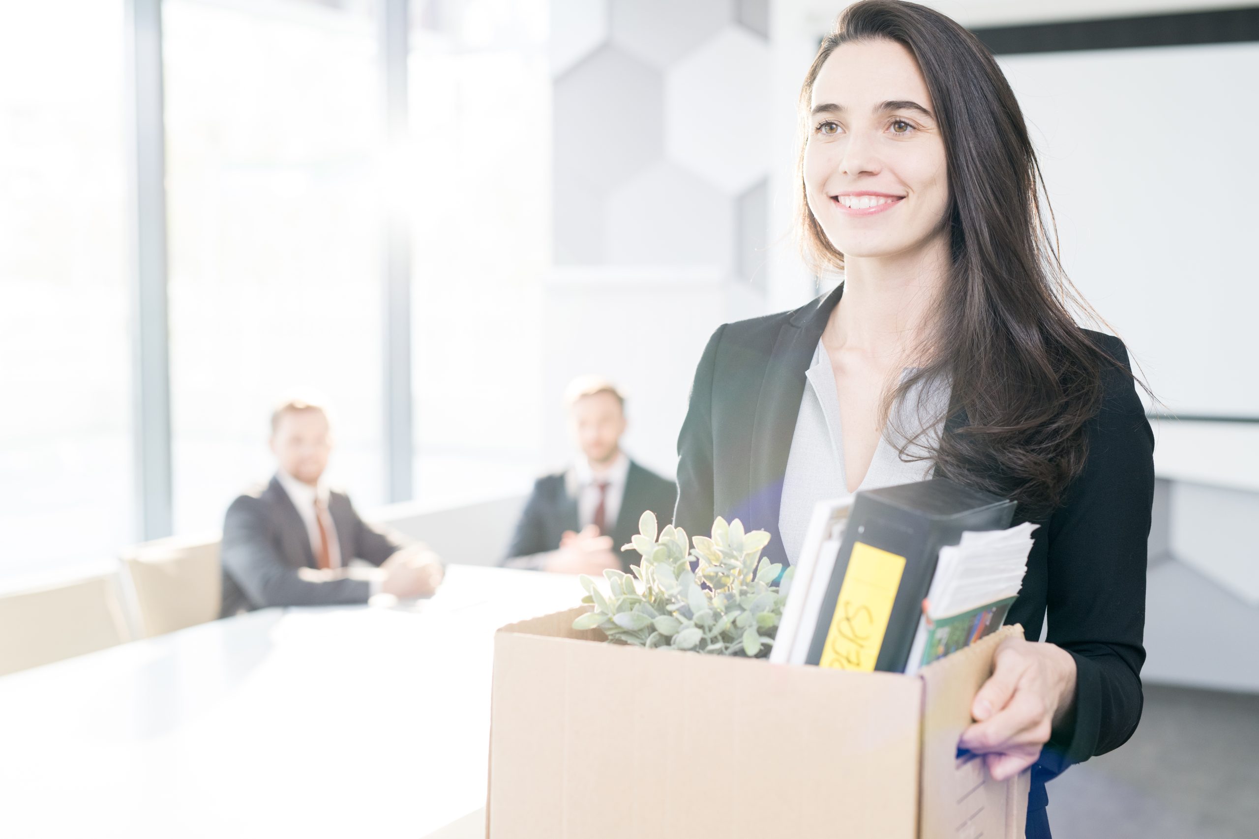 Waist up portrait of happy young businesswoman holding box of personal belongings leaving office after quiet quitting herjob, copy space
