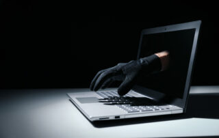 internet fraud and cyber attack concept. thief hand out of laptop