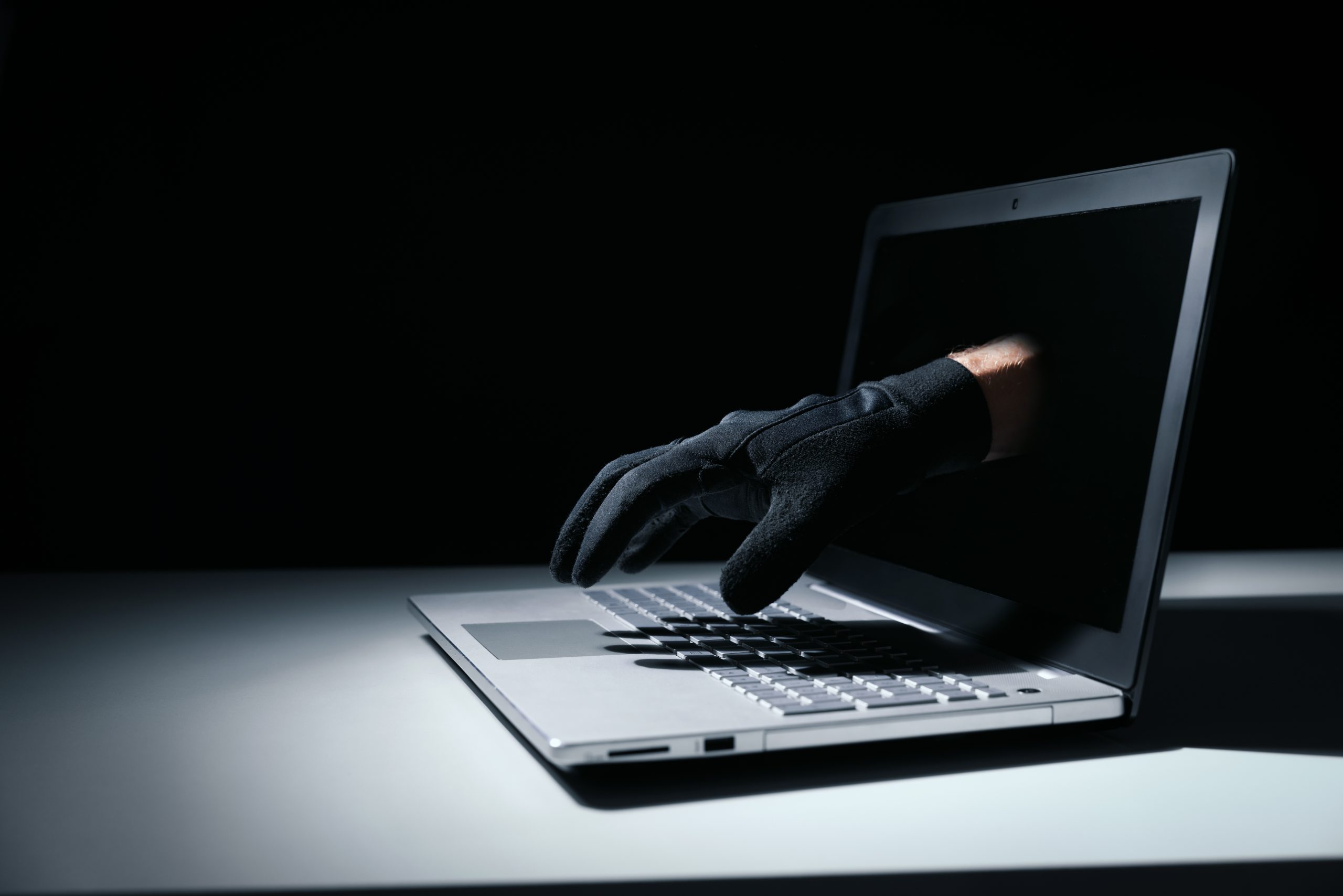 internet fraud and cyber attack concept. thief hand out of laptop