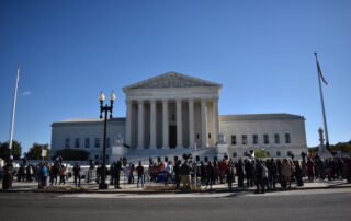 A large group of people gather outside a courthouse to peacefully protest