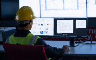 Construction worker sits in front of monitoring screen in hopes of preventing cyberattacks.