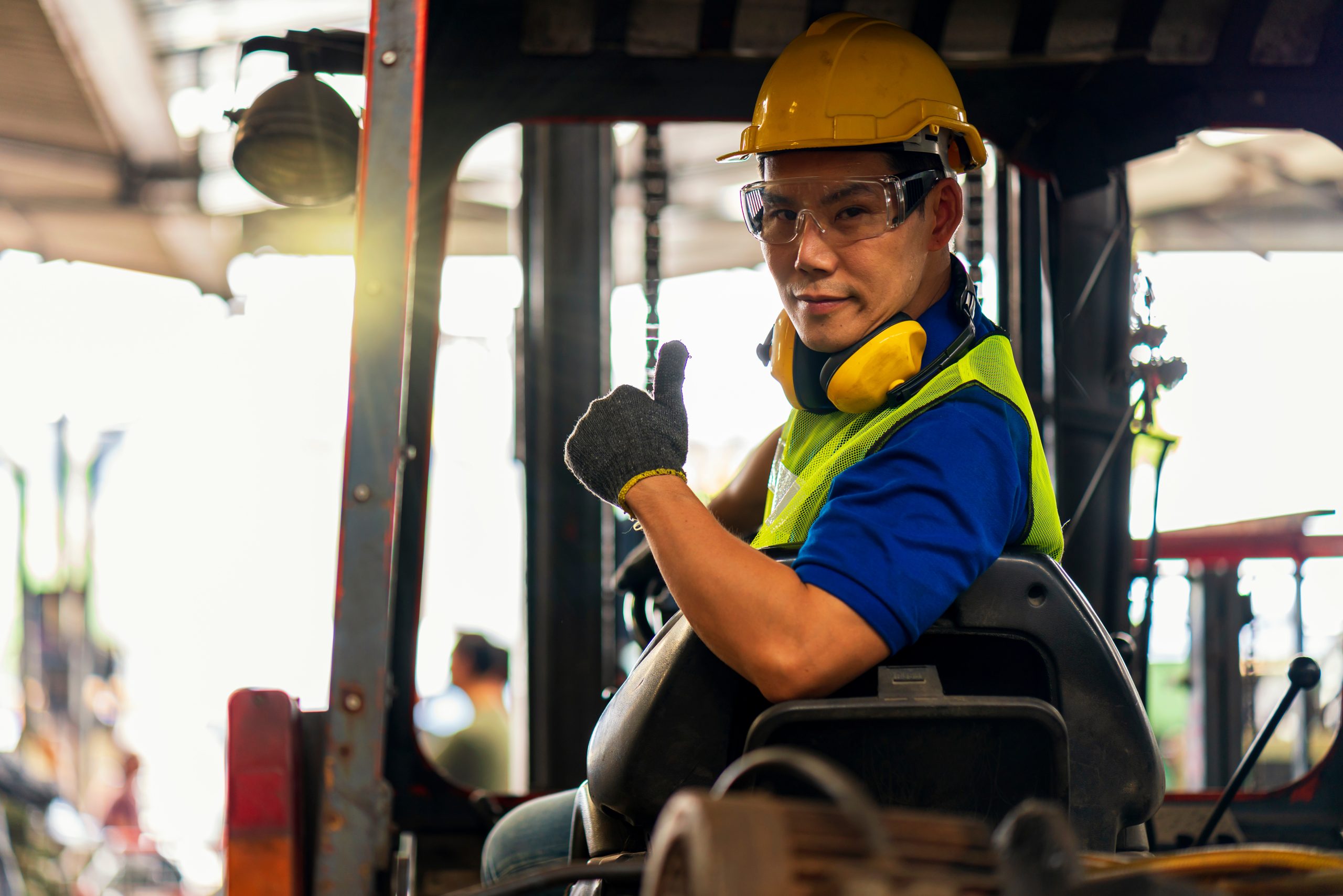 A male Engineer or technician driving a forklift. The driver is wearing eye protection to help prevent eye injuries.