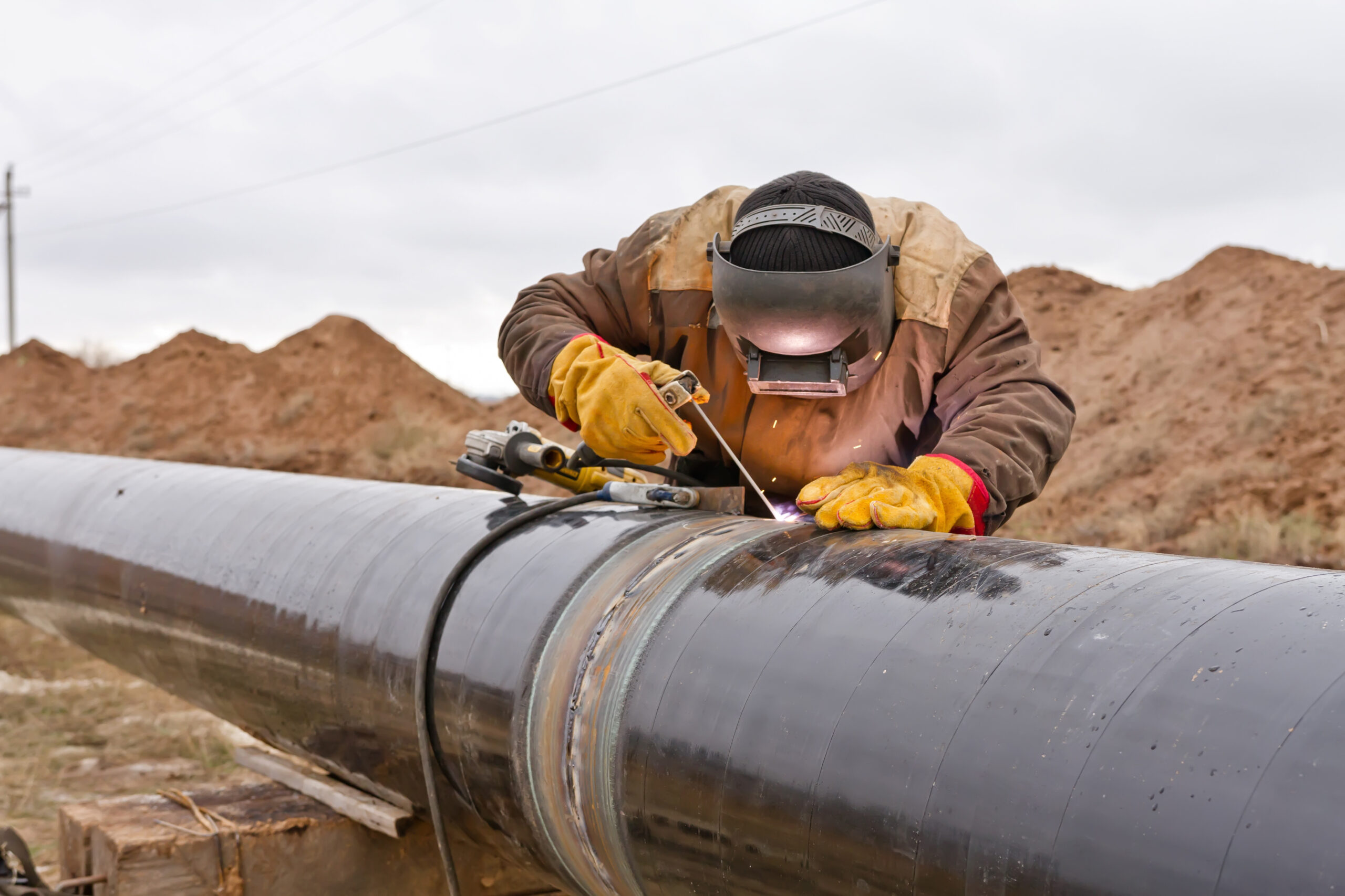 Welder works on a hot work project in the oil field.