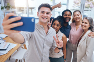 15 Low- and No-cost Employee Benefits to Offer: A group of employees taking a selfie after a meeting. One way to retain top talent is to offer extra benefits.