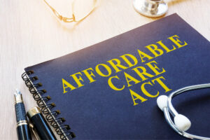 A blue medical journal with Affordable Care Act (ACA) in yellow. A stethoscope sits on top of the journal