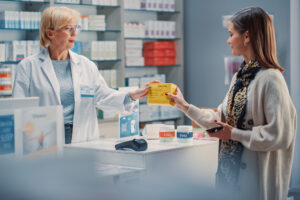 A female pharmacist handing a female customer her prescription.