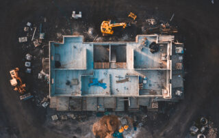 Aerial birds eye image of the frame of a house being built on a construction site at sunset - Wooden floor and walls are visible. Several attractive nuisances are visible