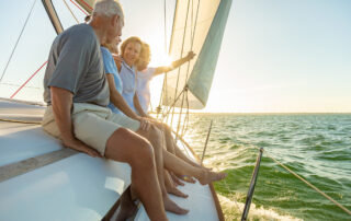 Relaxed group of senior American friends sailing towards horizon on luxury yacht enjoying freedom outdoors in retirement.