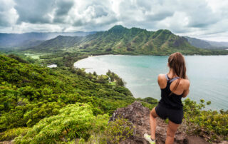 Sporty young woman on a mountain watching the impressive clouds over the distant peaks while on a sabbatical from work.