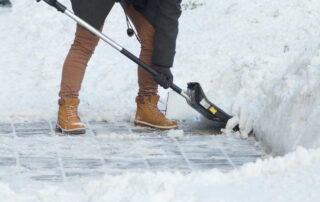 Business woman with shovel cleaning snow filled street in front of the office at work