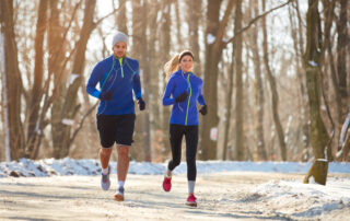 Young couple in the winter running together in nature