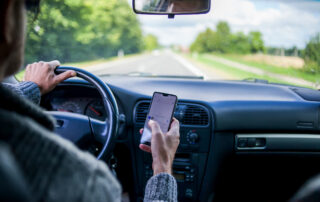 A man is using a cell phone doing what is considered distracted driving.