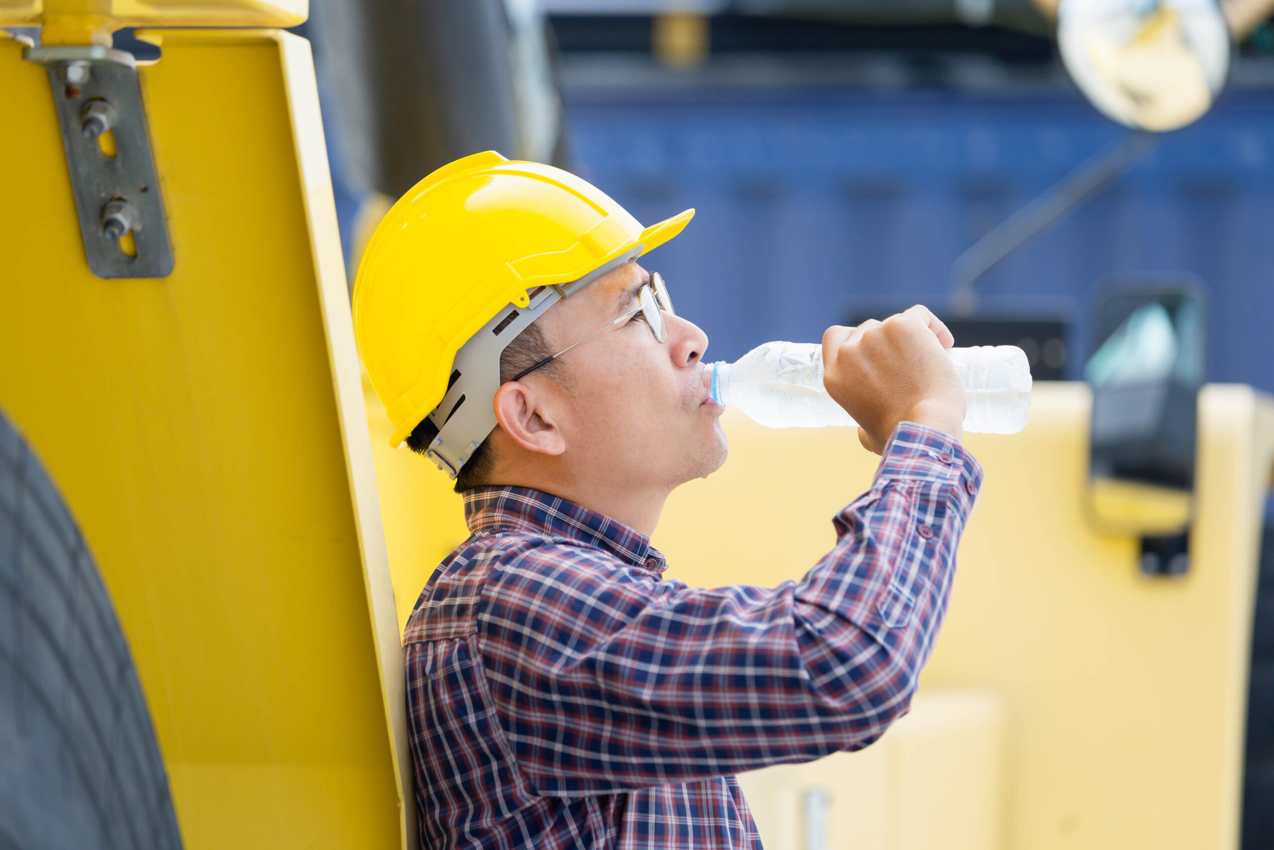 Worker man in hard hat drinking water, participating in a heat safety program.