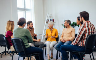 Supporting Employee Mental Health : Photo of serious-looking people, talking to each other during group therapy.