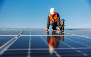 A worker installing solar panels on the roof.