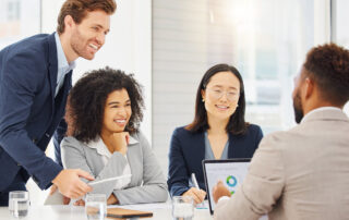 A diverse group of people sitting around a table discussing tips to drive revenue and efficiency using data.