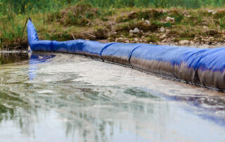 Floating blue oil arrow on calm water, serving as a barrier to spilled oil. The concept of pollution.