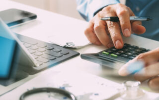 Major Changes in HSA and HDHP for 2024: a person sitting at a desk with a calculator, pen and paper and laptop