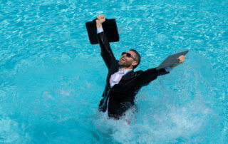 Four Strategies Radically Transforming Employee Well-Being: businessman in wet suit excited jumping in swim pool.