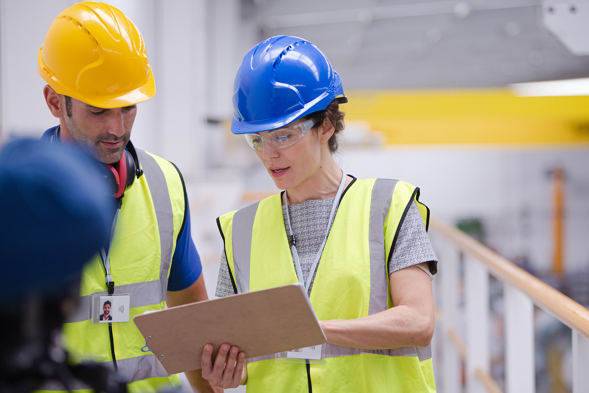 A department lead going over paperwork with a fellow construction colleague. The review of return-to-work policies help prevent medical mismanagement.