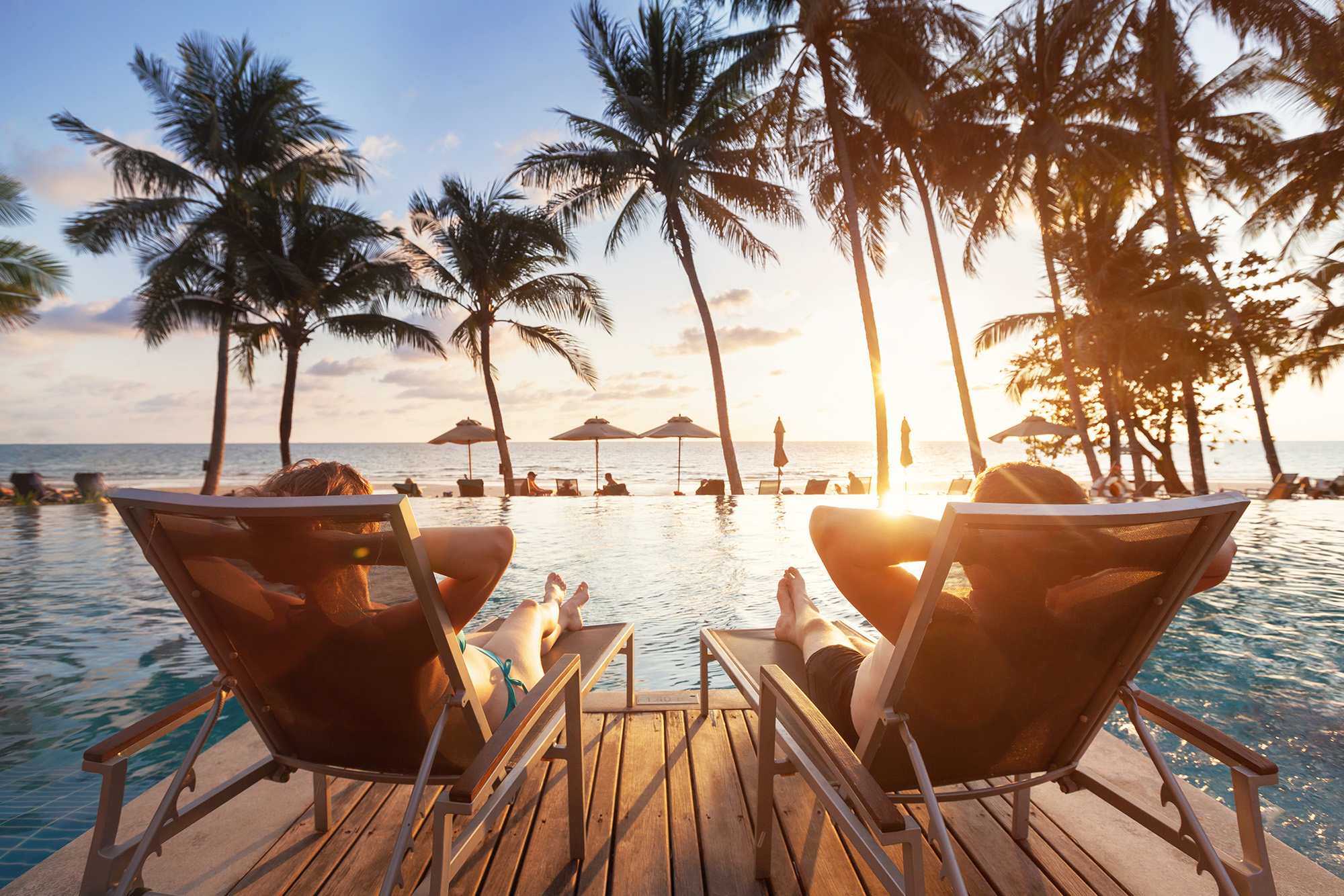 Unlimited PTO Gaining Traction: Is Now the Time?: two people sitting on chairs near a pool watching a sunset.
