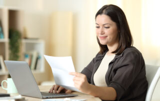 2024 Open Enrollment: Woman reading a letter using laptop at home