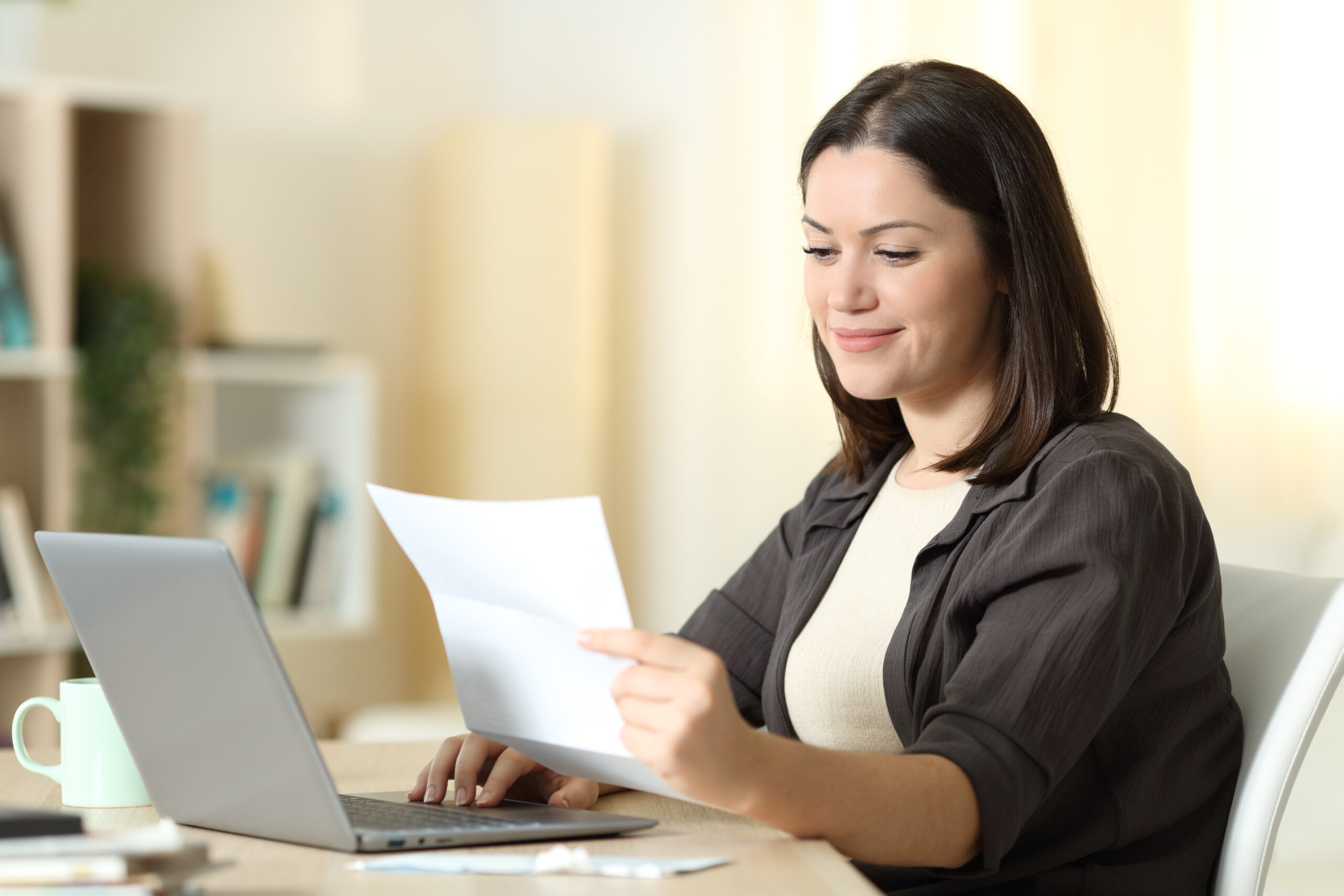 2024 Open Enrollment: Woman reading a letter using laptop at home