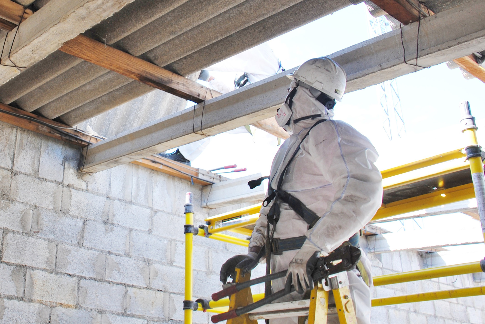 Safety Matters: Asbestos Awareness: A construction worker in a hazmat suit disposing of asbestos in an old warehouse.