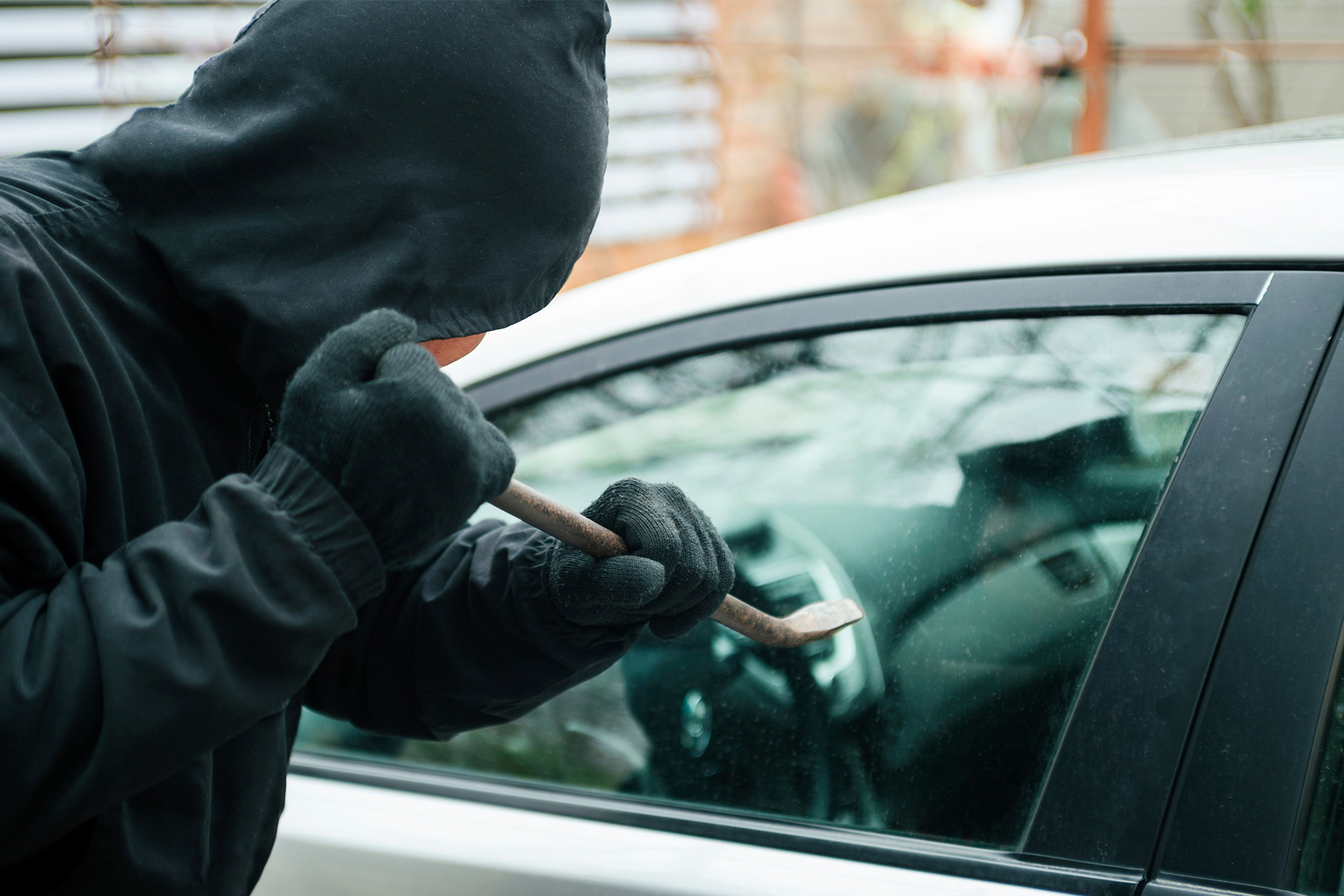 2023 Top Auto Hazards: A thief breaking into a car with a crowbar.