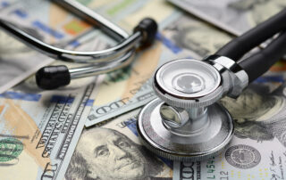 Average Data Breach Cost Hits All-time High of $4.4M: Medical stethoscope on heap of dollar bills. Health care or insurance costs concept. Finance banking audit analytics.