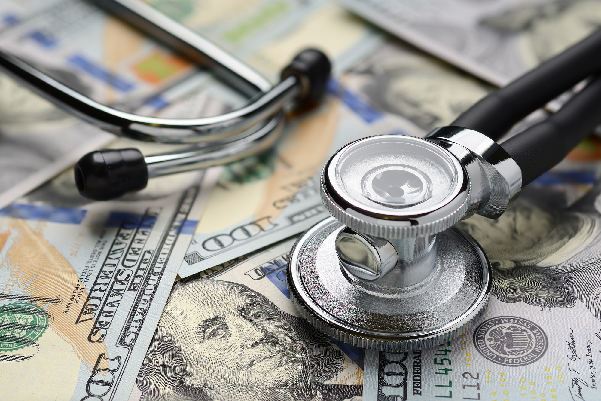 Average Data Breach Cost Hits All-time High of $4.4M: Medical stethoscope on heap of dollar bills. Health care or insurance costs concept. Finance banking audit analytics.