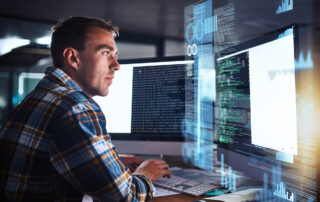 Managing Cyber Security During a Merger or Acquisition: A man sitting at a computer working on IT issues.