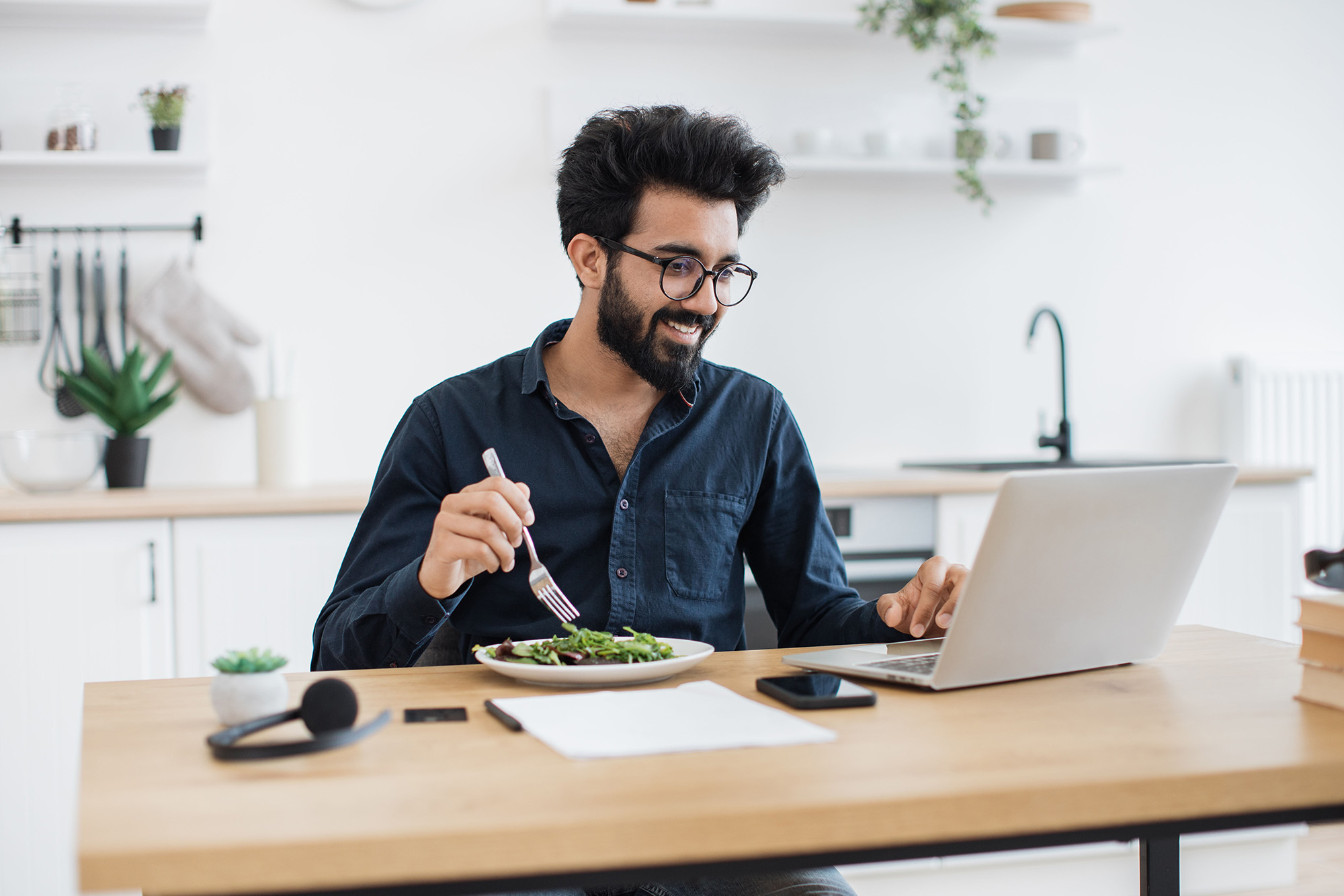 Rethink Your Healthcare Offerings: a man sitting at his desk, eating a salad while working remotely.