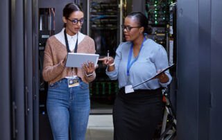 Importance of Privacy and Cybersecurity: Two female IT professionals working in a server room.