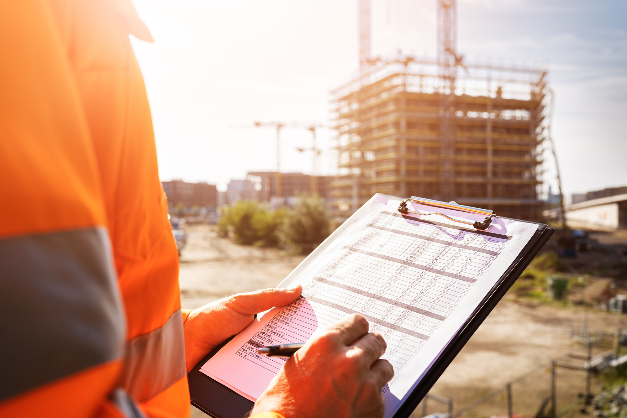 OSHA Announces Top 10 Violations for 2023: a construction worker on a job site writing notes on a clipboard.