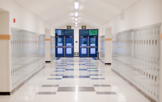 Best Practices for Efficient Claim Reporting and Management: An empty school hallway with lockers on each side and an exit door at the far end.