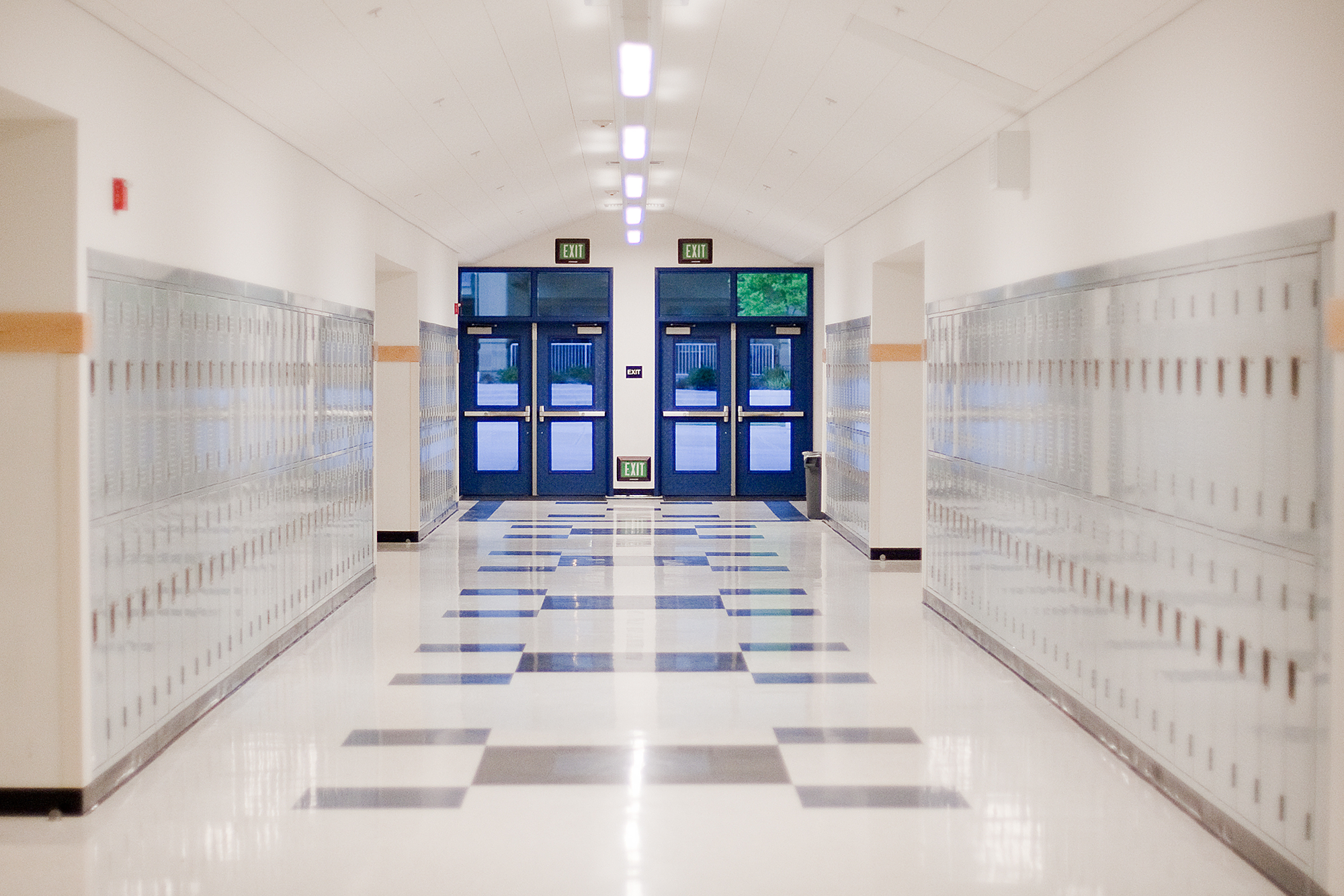 Best Practices for Efficient Claim Reporting and Management: An empty school hallway with lockers on each side and an exit door at the far end.