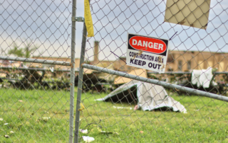 Tornado Preparedness Tips for School Administrators: A storm damaged school blocked off by a chain-linked fence with a keep out sign posted at the entrance.