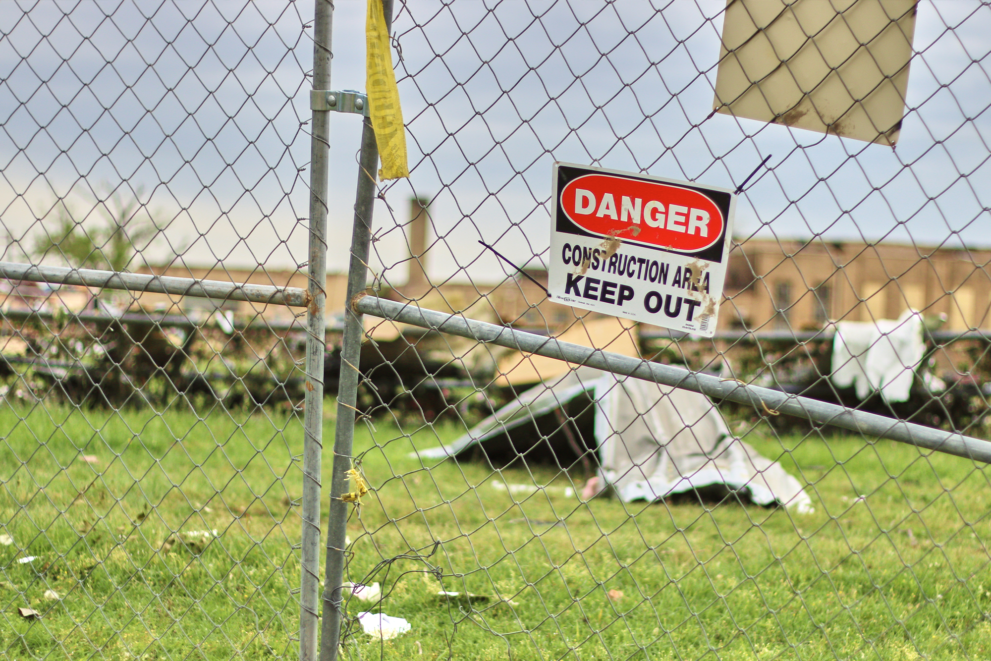 Tornado Preparedness Tips for School Administrators: A storm damaged school blocked off by a chain-linked fence with a keep out sign posted at the entrance.