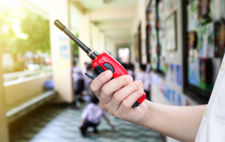 Effective Communication During Emergencies: School Alert Systems - A school administrator with a two-way radio in their hand while standing in a hallway.