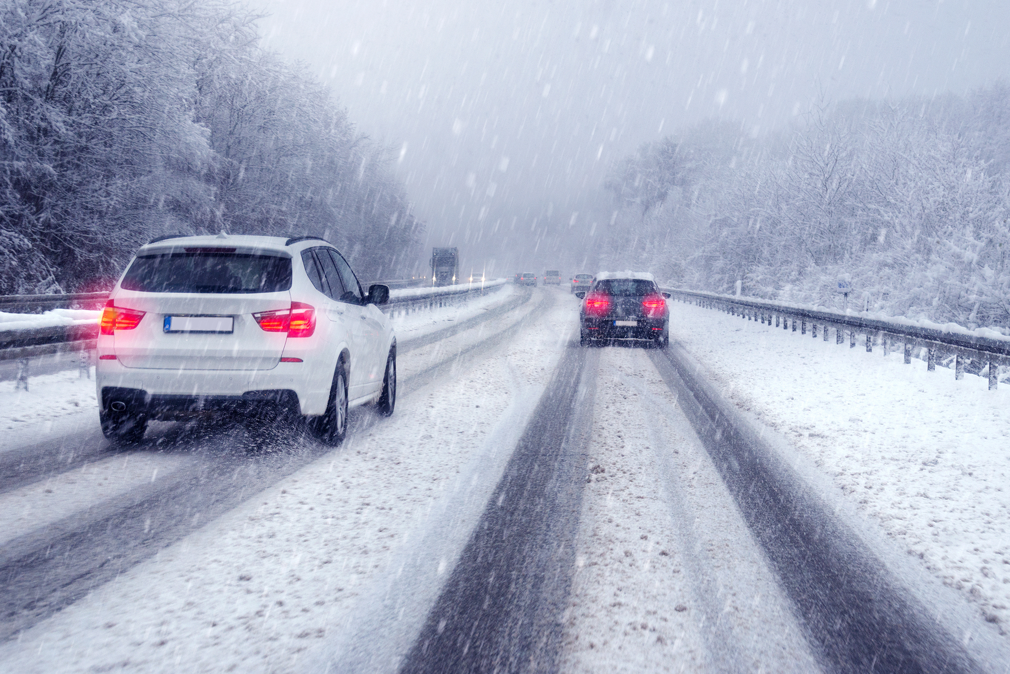 Winter Driving safety Tips: Two cars travelling the same direction on a snow-covered road.