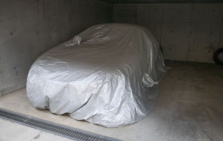 Winter vehicle storage: A car properly stored in a garage with a cover over the vehicle.