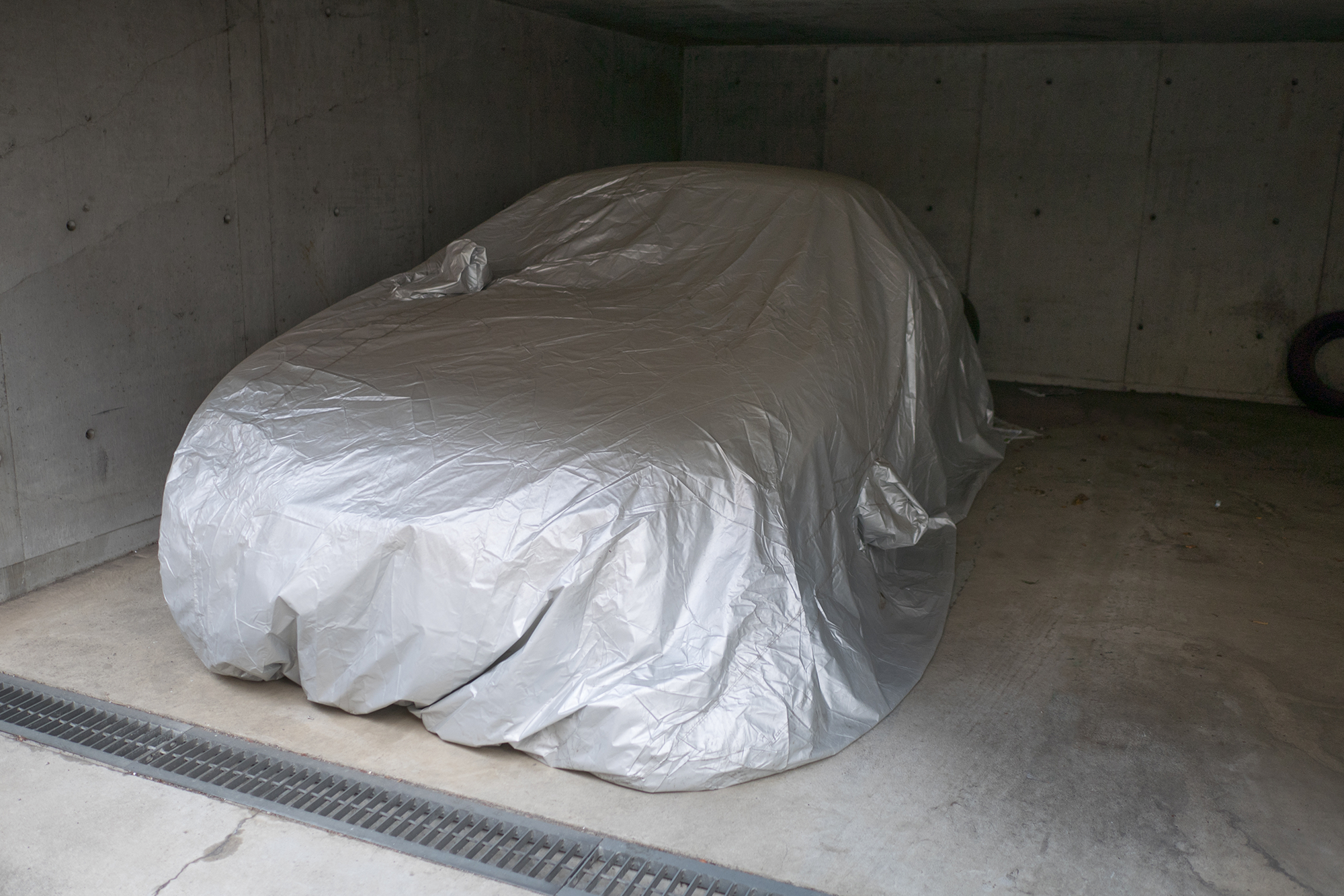 Winter vehicle storage: A car properly stored in a garage with a cover over the vehicle.