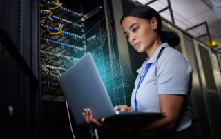 10 Essential Cybersecurity Controls: A young female IT professional logging in to a server with her laptop.