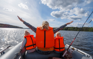 Boating Safety Tips: A woman with two young children on either side, all wearing life jackets on a boat.