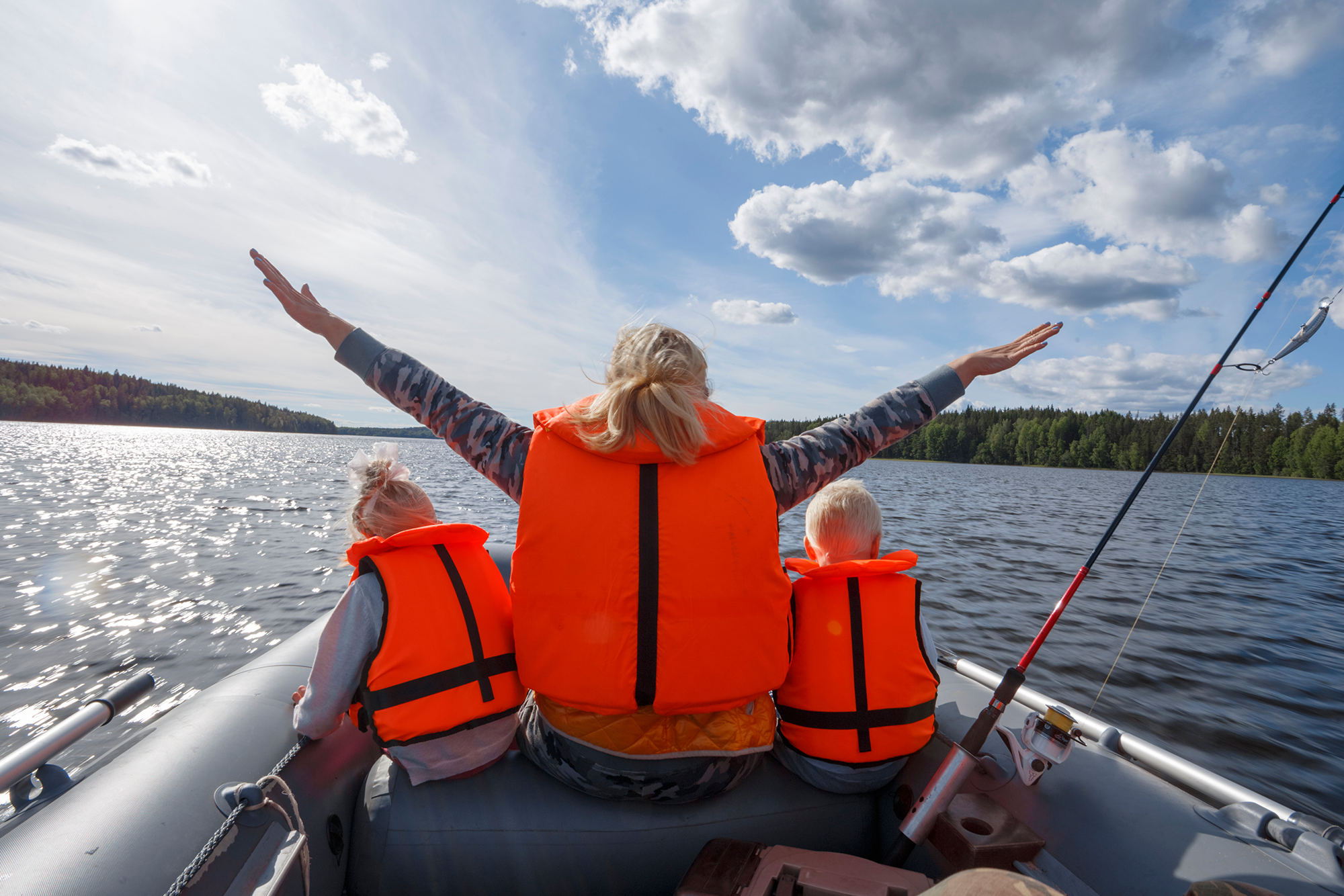 Boating Safety Tips: A woman with two young children on either side, all wearing life jackets on a boat.