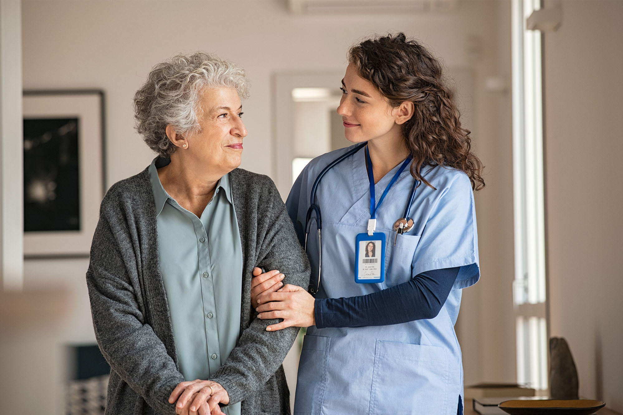Best Practices for Patient Safety in Healthcare Facilities: A female nurse escorting an elderly patient in a hospital.