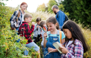 Navigating Liability Risks on School Field Trips: A group of small school children with teacher on field trip in nature, learning science.